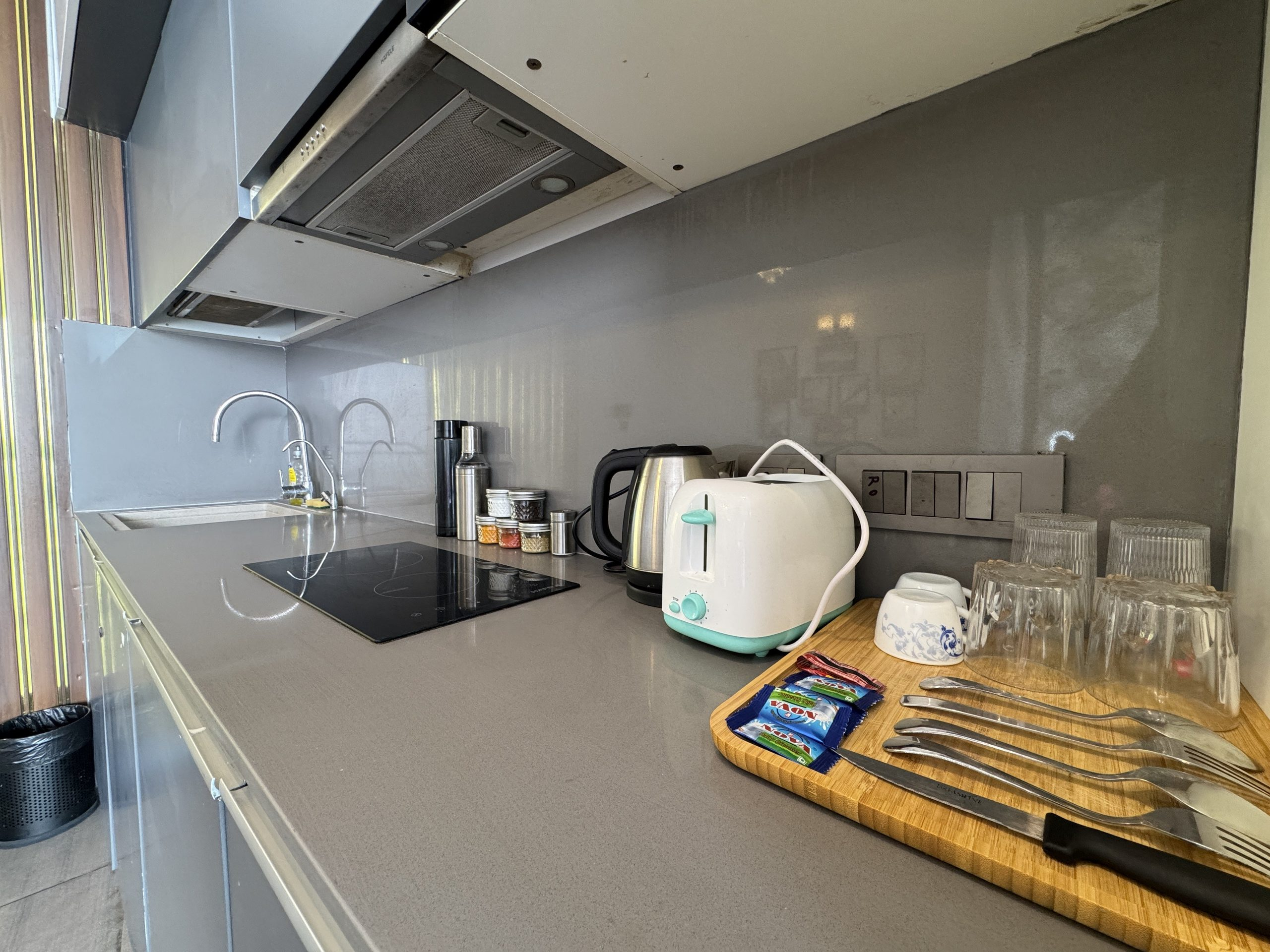Kitchenette with induction cooktop and appliances at UrbanAura Studio 37, service apartment in Noida