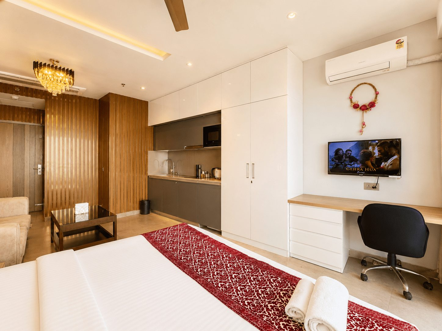 Wardrobe, work desk and TV beside the kitchenette at UrbanAura Studio 37, Supernova room price from ₹3,500