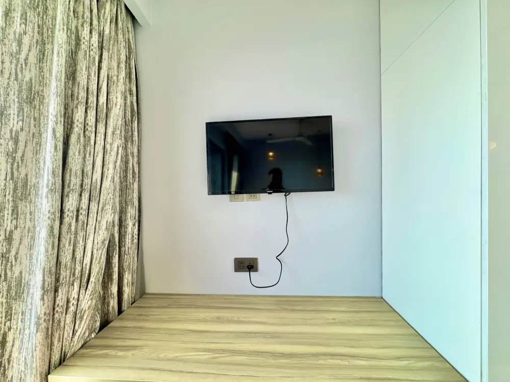 Bedroom with wall-mounted TV and built-in wardrobe at Spira Apartments Supernova Noida – Mulberry Homes